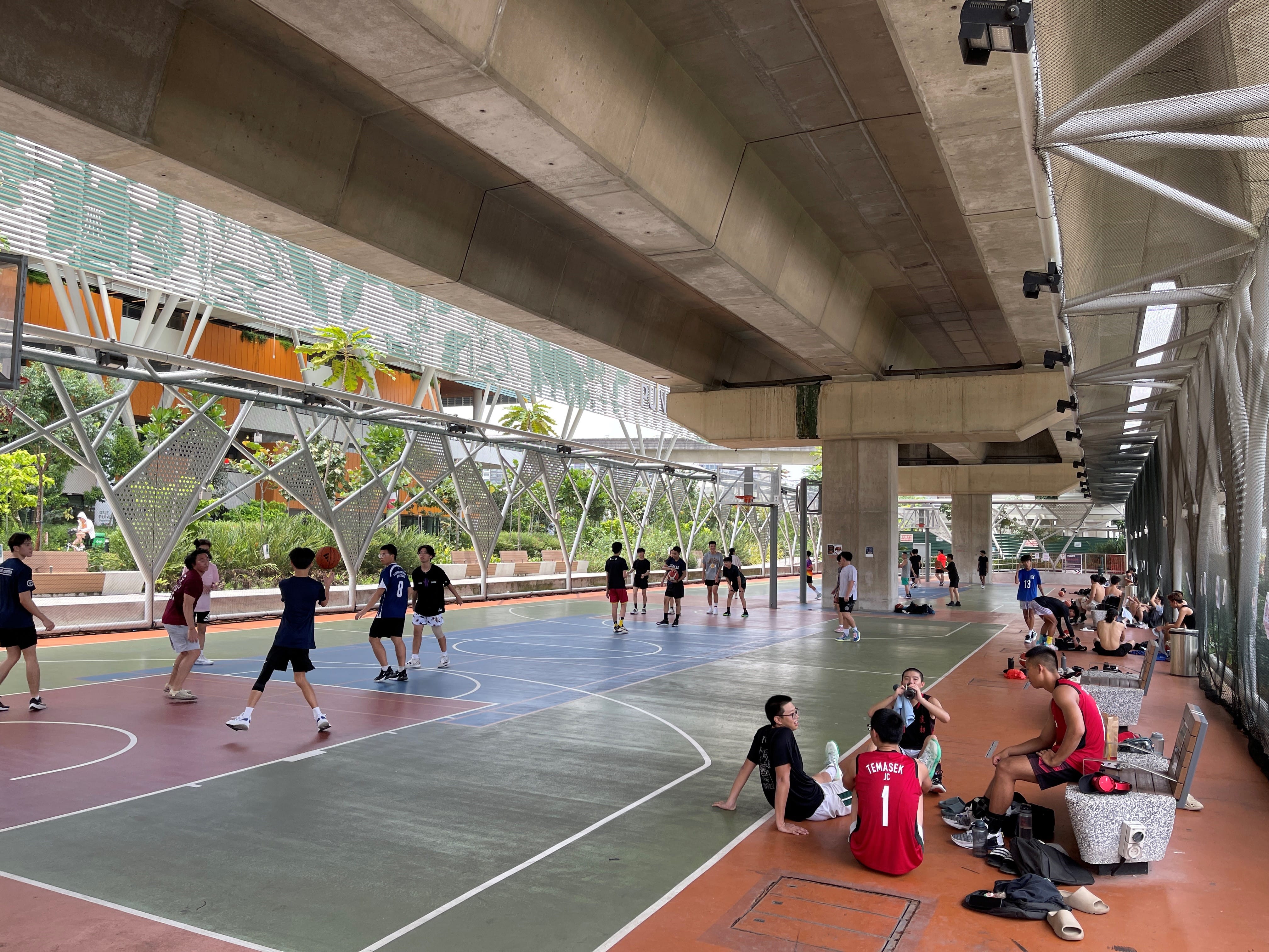 People playing sports at court below MRT track